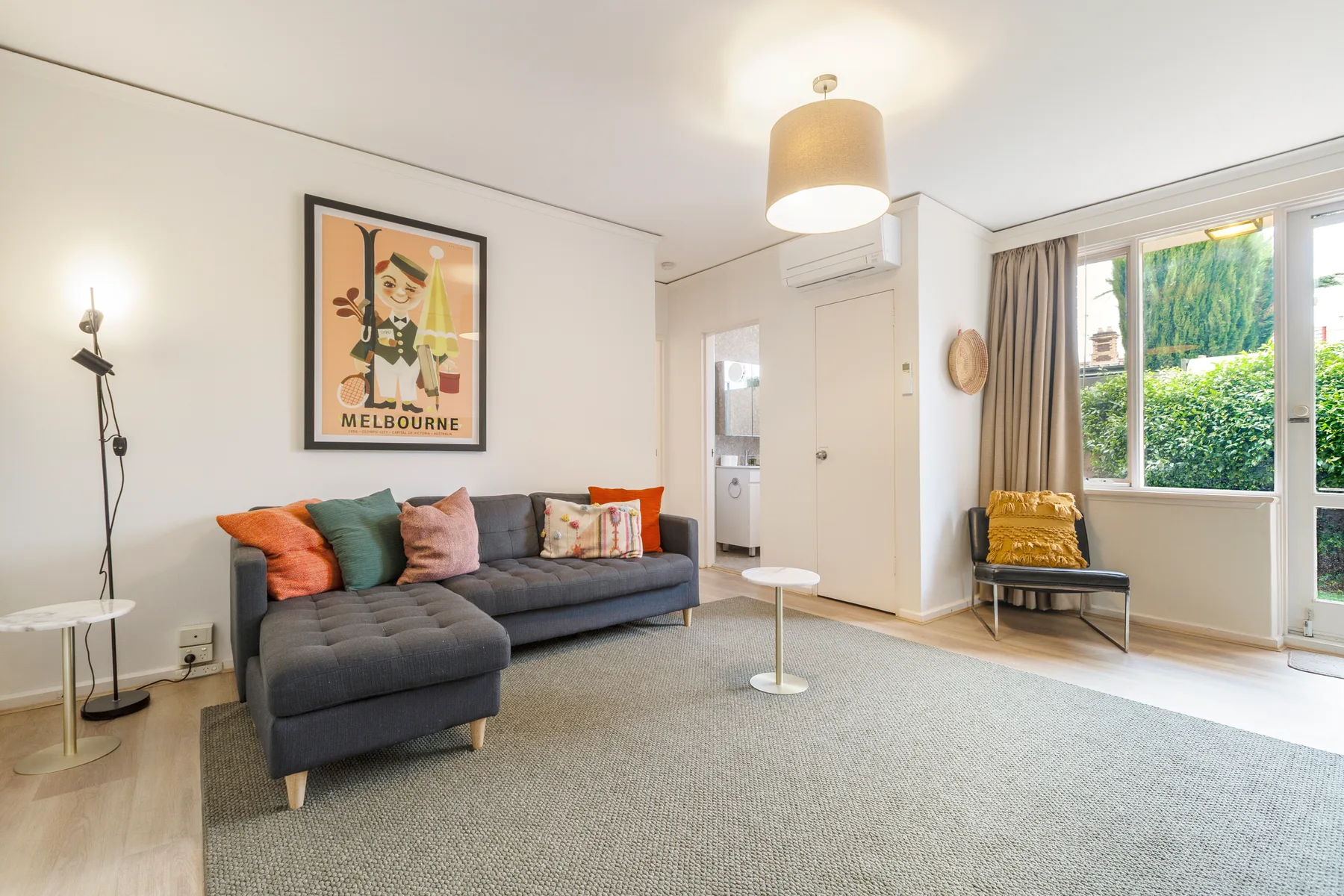 La sala de estar es un espacio fresco y vibrante, con cuadros de estilo retro y cojines de colores vivos sobre la acogedora chaise longue.