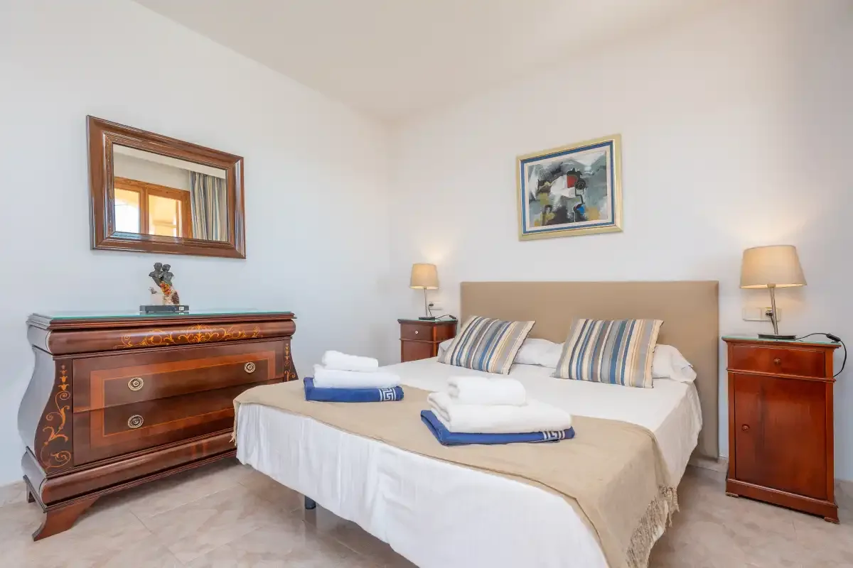 A bedroom with a neatly made bed and matching bedside tables.