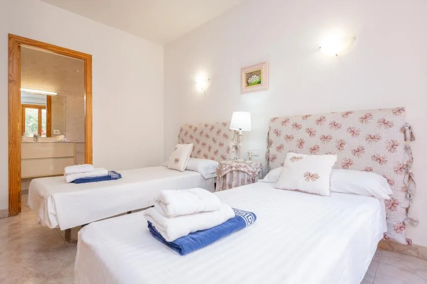 A bright bedroom with two beds and floral-patterned headboards.