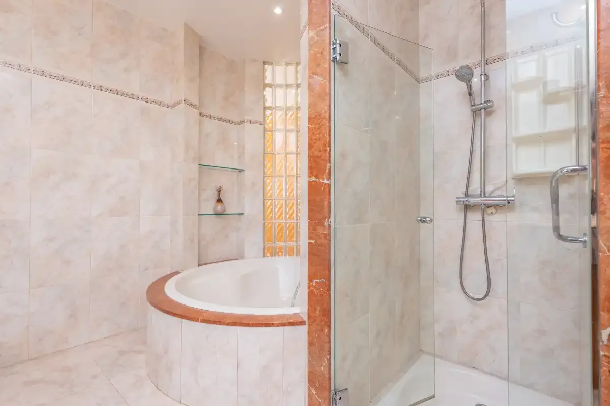A tiled bathroom with a bathtub and glass shower.