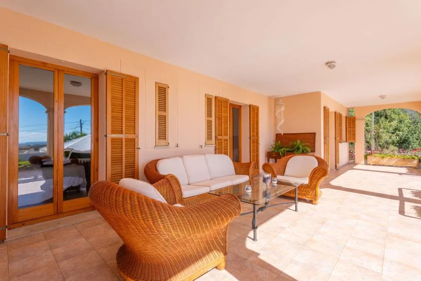 Covered patio seating area with wicker furniture and a glass coffee table.