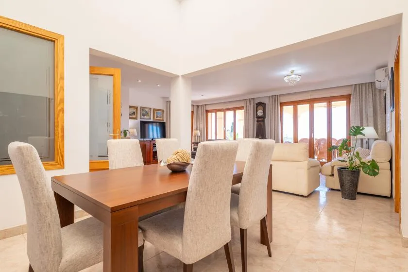 A dining area opens into a living room with seating and large windows.