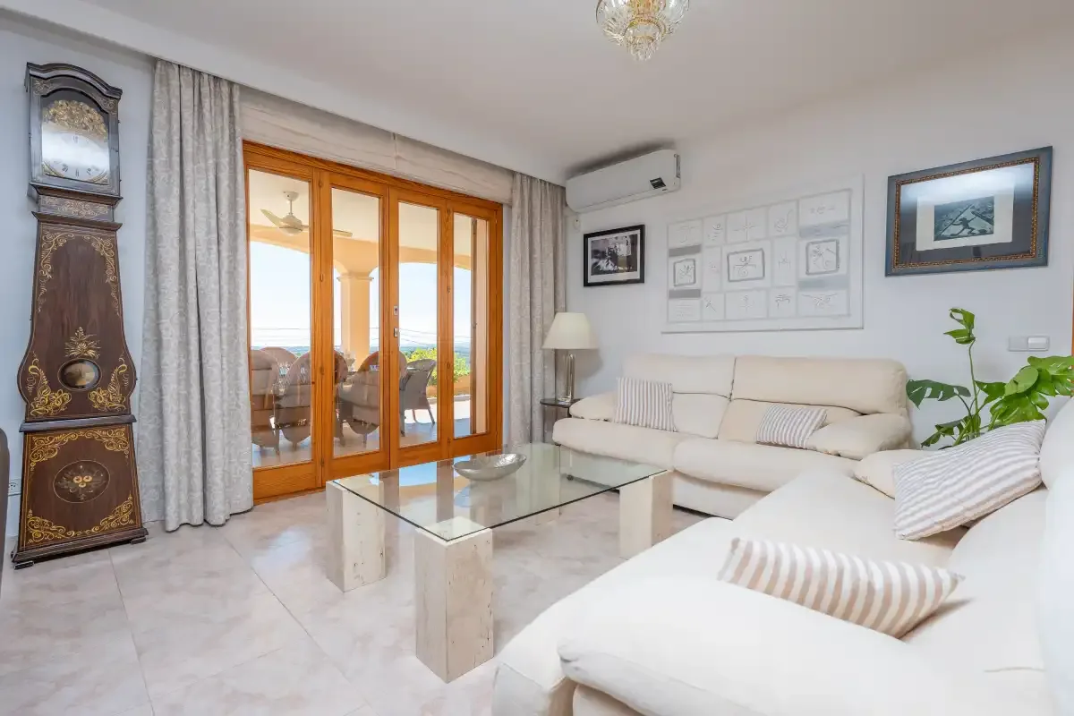 A bright living room with light seating and glass doors opening to a balcony.