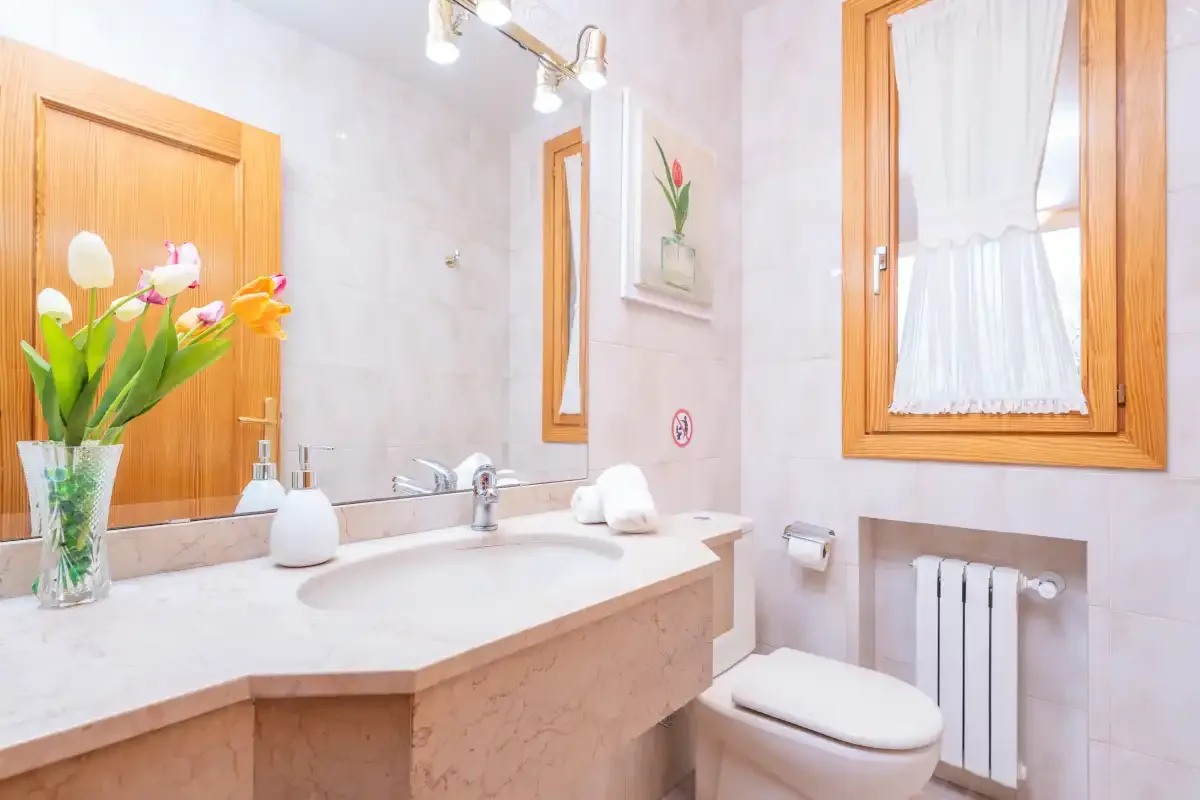 A bright bathroom with a wide vanity, sink, and window.