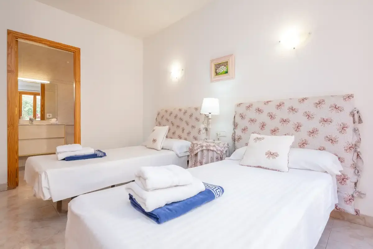 A bright bedroom with two beds and floral-patterned headboards.