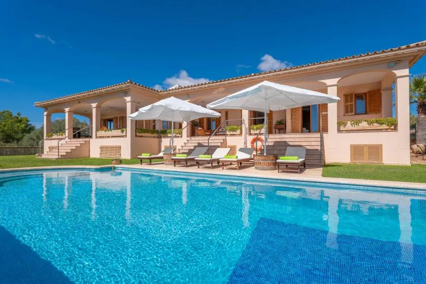 A house with a swimming pool, patio seating, and umbrellas.