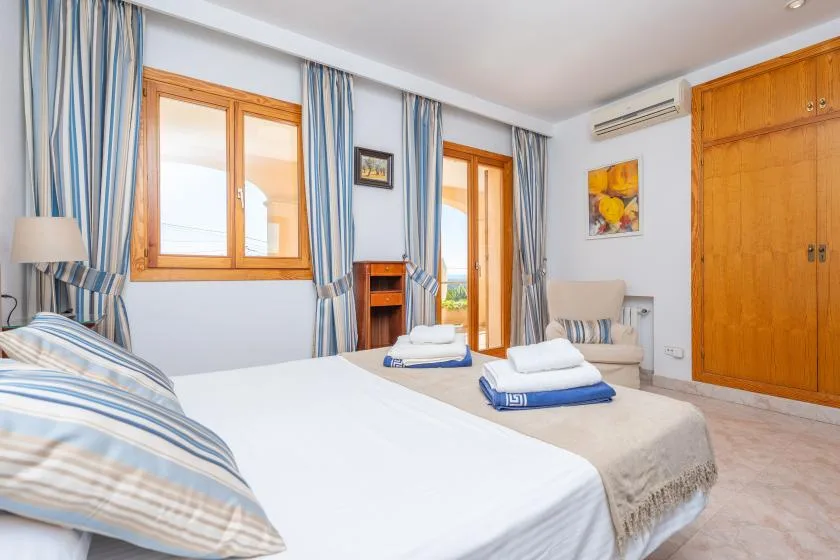 A bedroom with a bed, striped curtains, and wooden wardrobes.