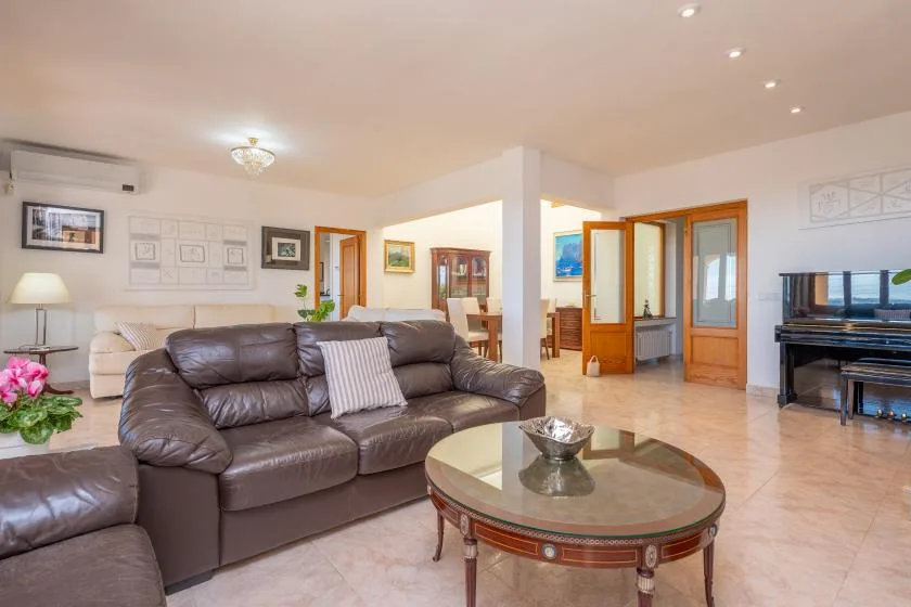 A bright living room with a leather seating area and oval glass coffee table.