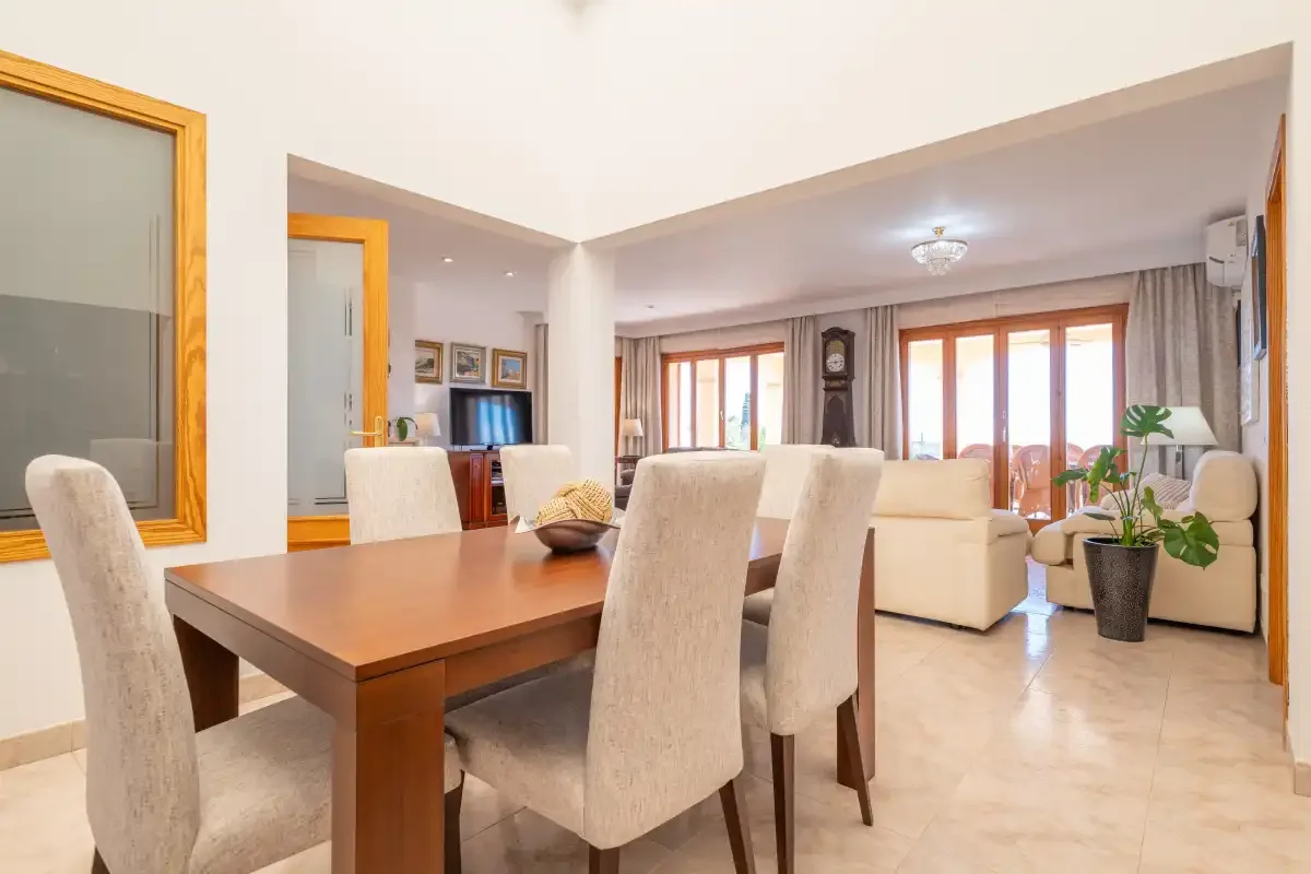 A dining area opens into a living room with seating and large windows.
