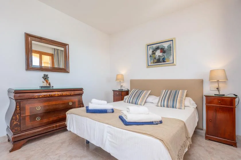 A bedroom with a double bed, striped pillows, and wooden bedside tables.