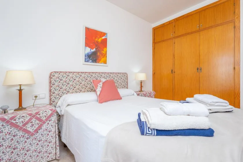 A bedroom with a double bed, patterned headboard, and wooden wardrobes.