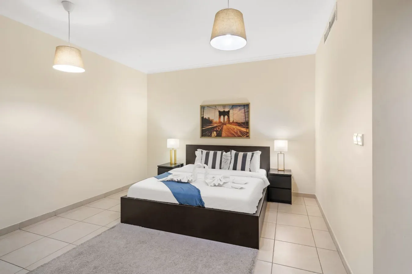 A bedroom with a bed, bedside tables, and framed artwork above the headboard.