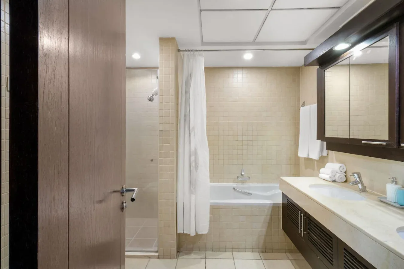 A tiled bathroom with a bathtub, shower curtain, and sink.