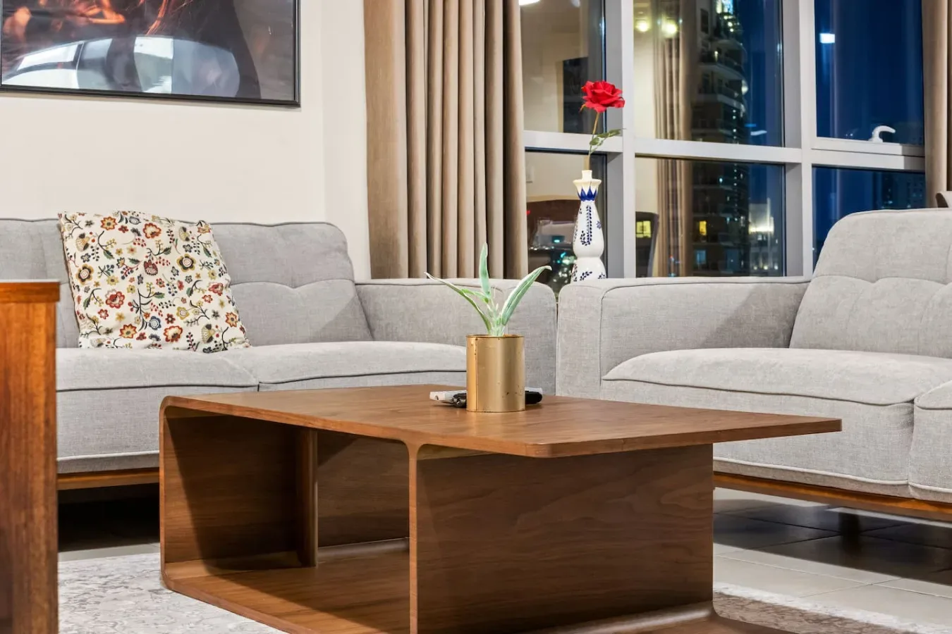 A living room with gray seating, a wooden coffee table, and large windows.