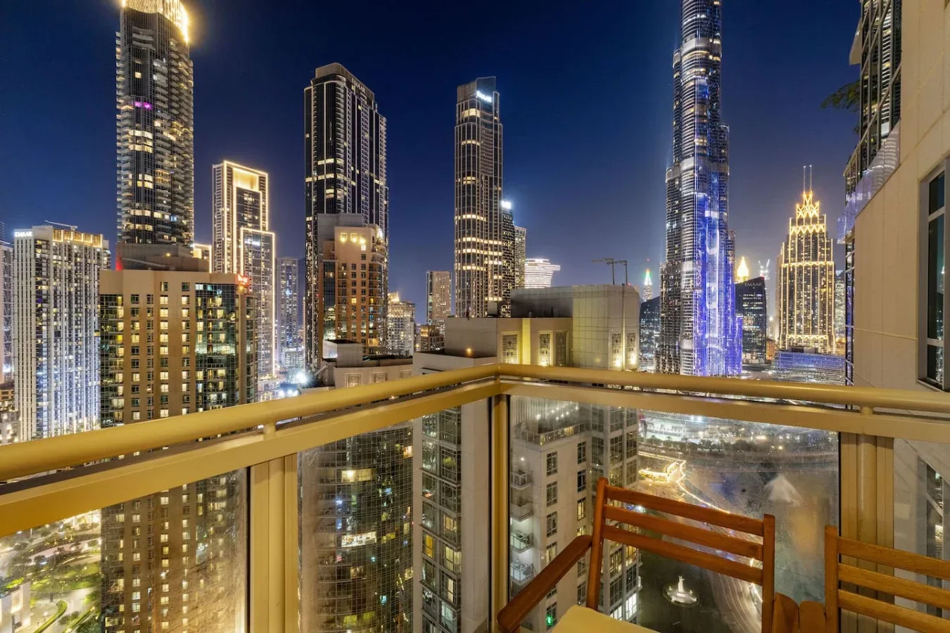 A balcony overlooks a brightly lit city skyline at night.