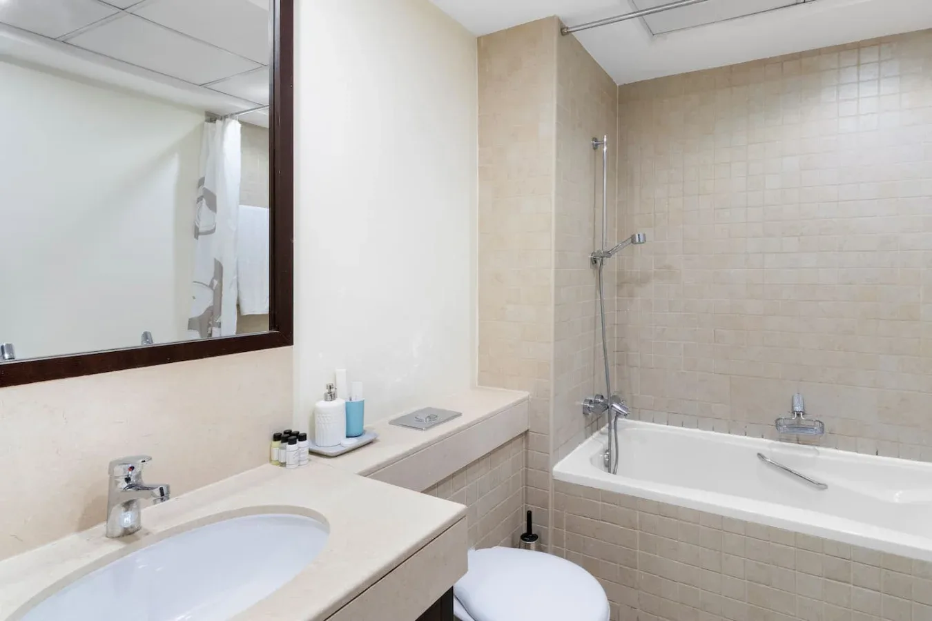 A bathroom with a sink, mirror, and bathtub.