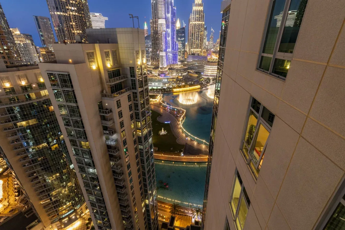 Nighttime city view of illuminated high-rise buildings beside a curving waterfront.