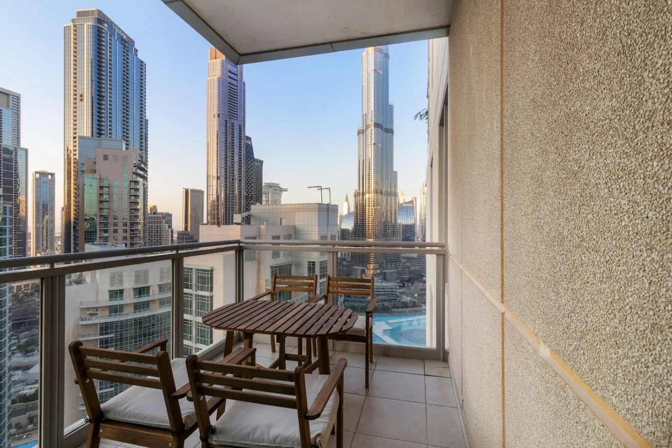 A balcony seating area overlooks a city skyline and a swimming pool.