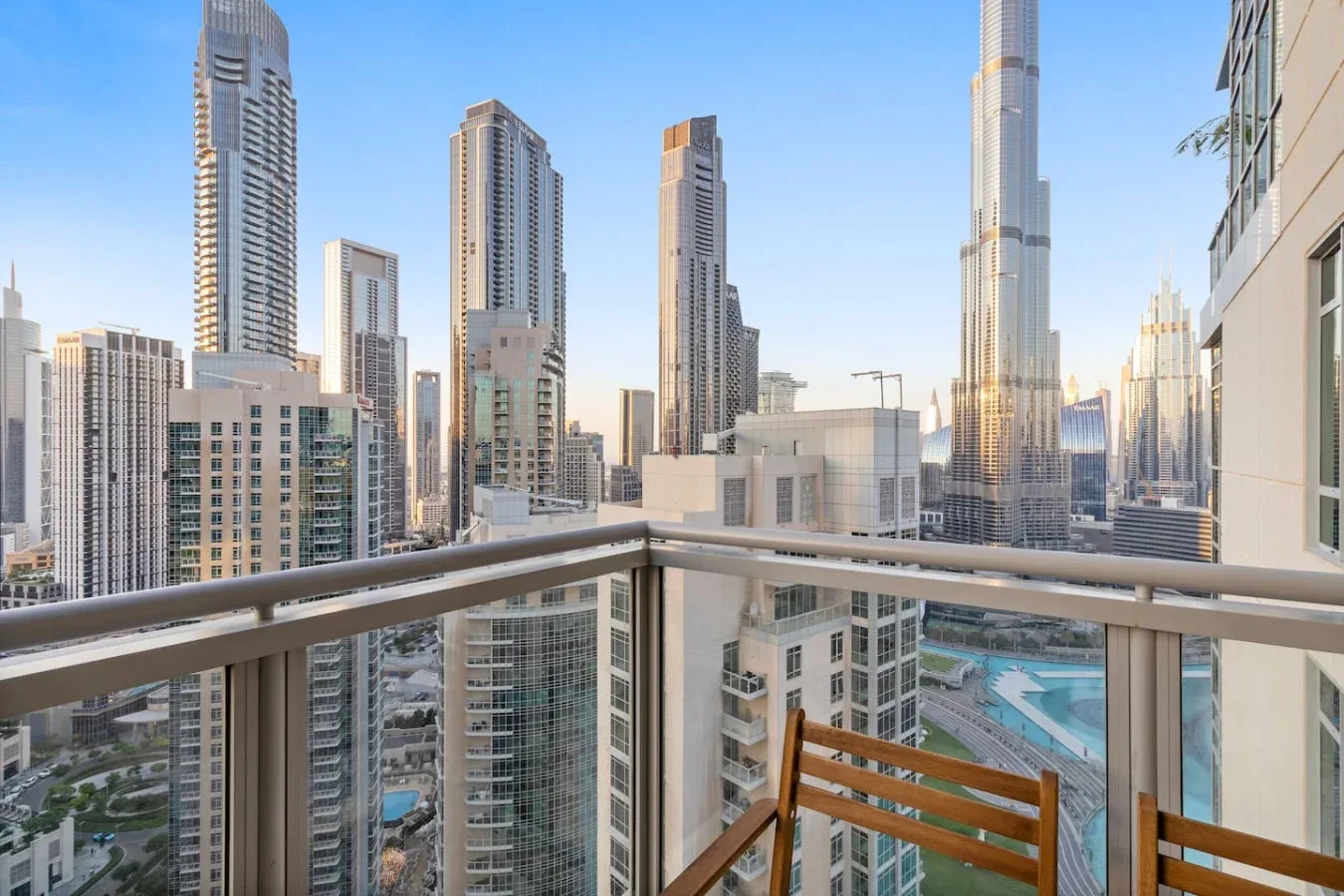 A balcony overlooks a city skyline, with wooden seating beside the railing.