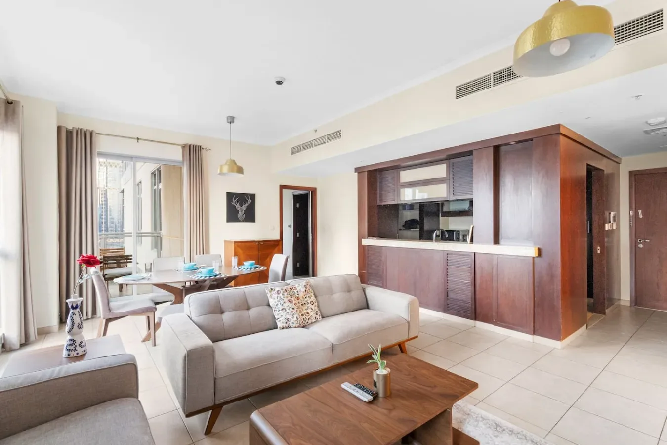 A bright living room with seating and a dining area beside a built-in kitchen.