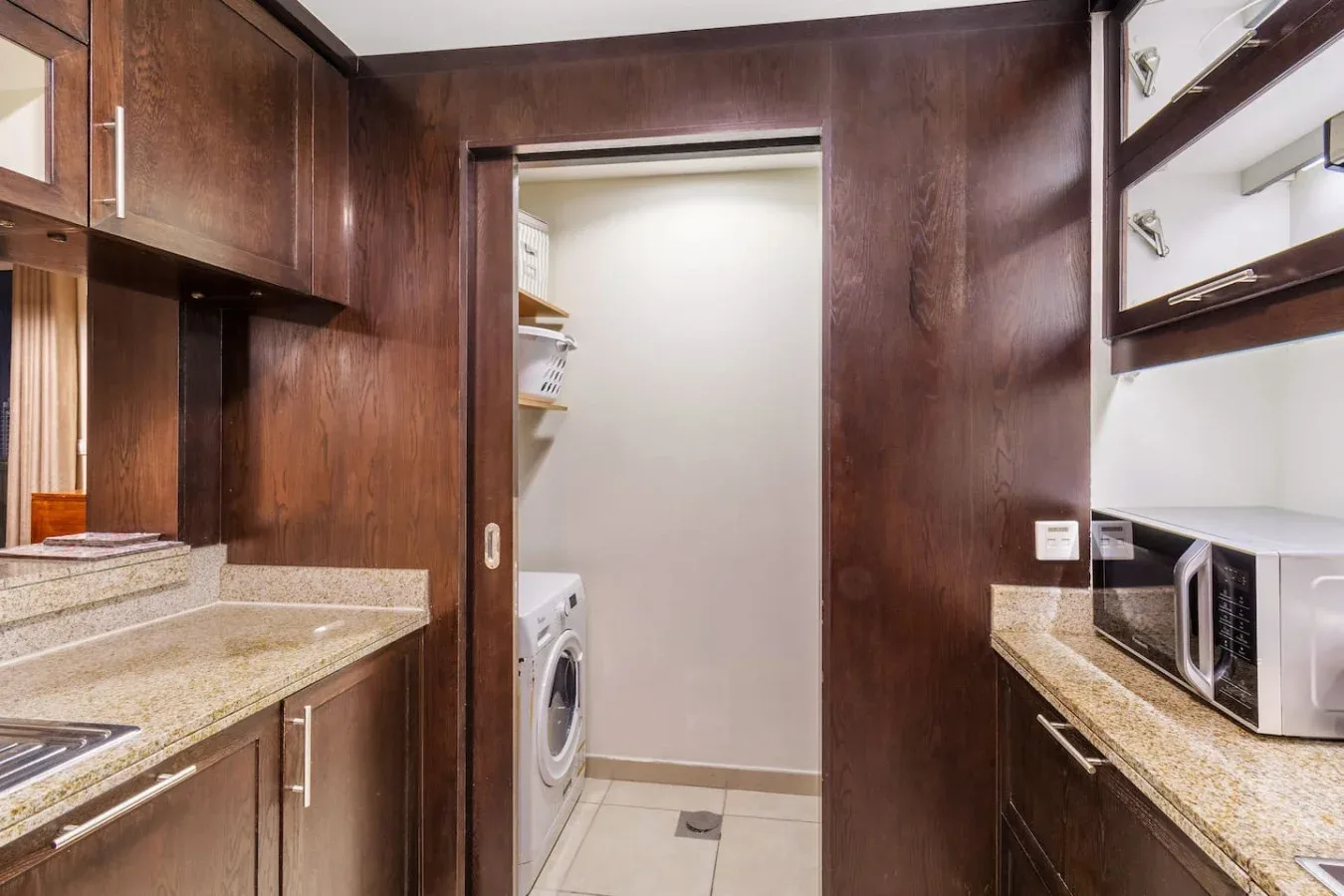 A compact laundry area with a washer between dark wood cabinets and countertops.