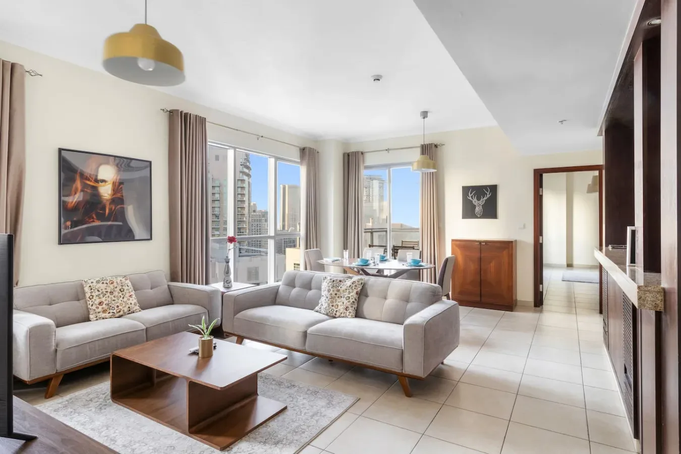 A bright living room with seating, a coffee table, and large windows.