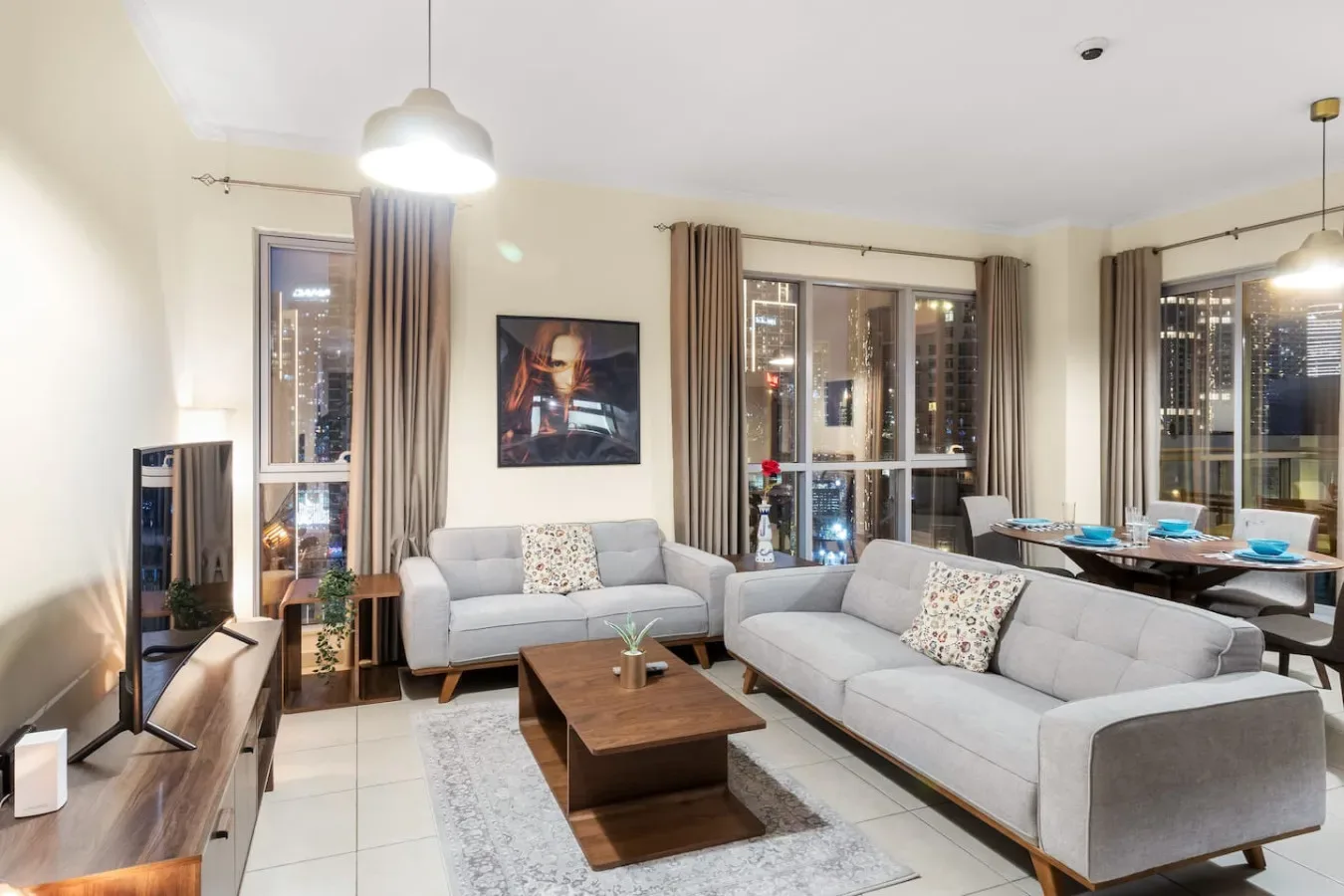 A bright living room with light-colored seating, a coffee table, and tall windows.
