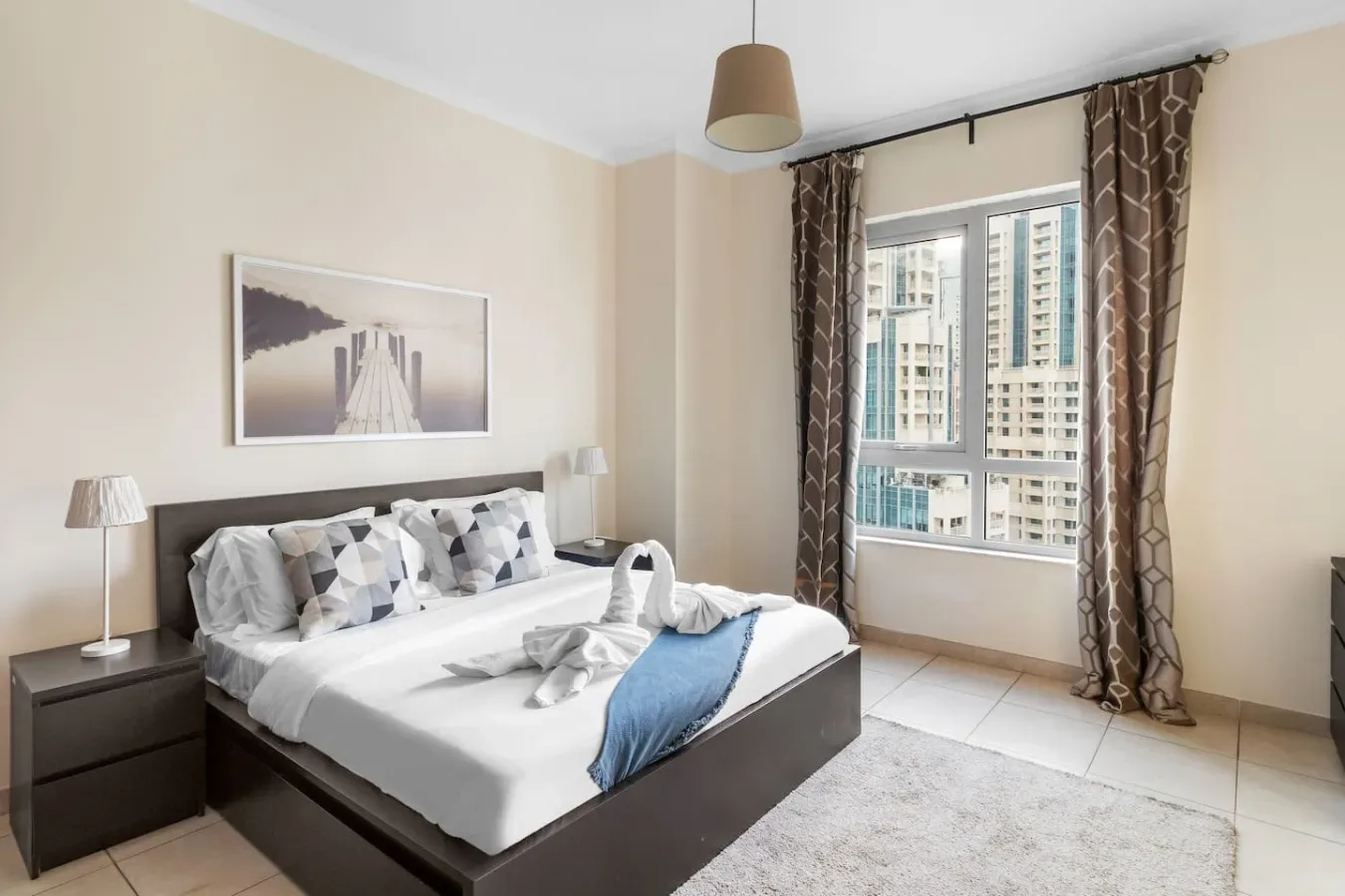 A bedroom with a neatly made bed beside a large window.