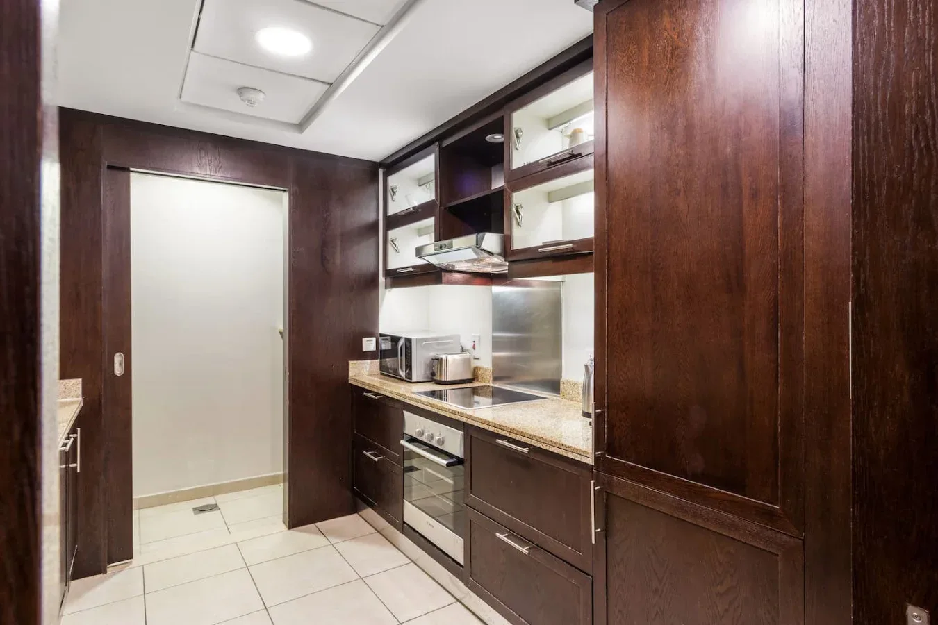 A compact kitchen with dark cabinetry, a countertop, and an oven.