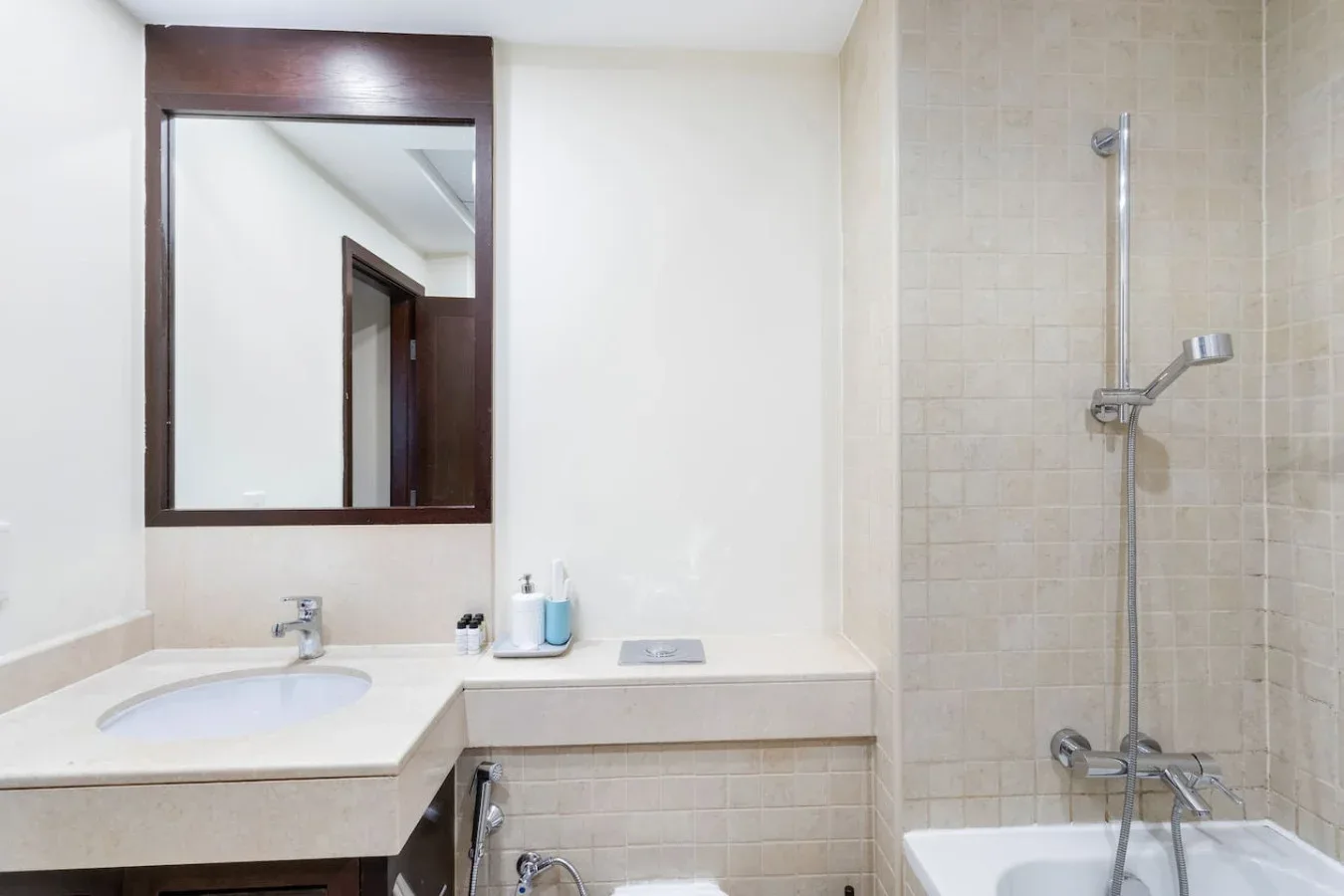 A bathroom with a sink, mirror, and shower.