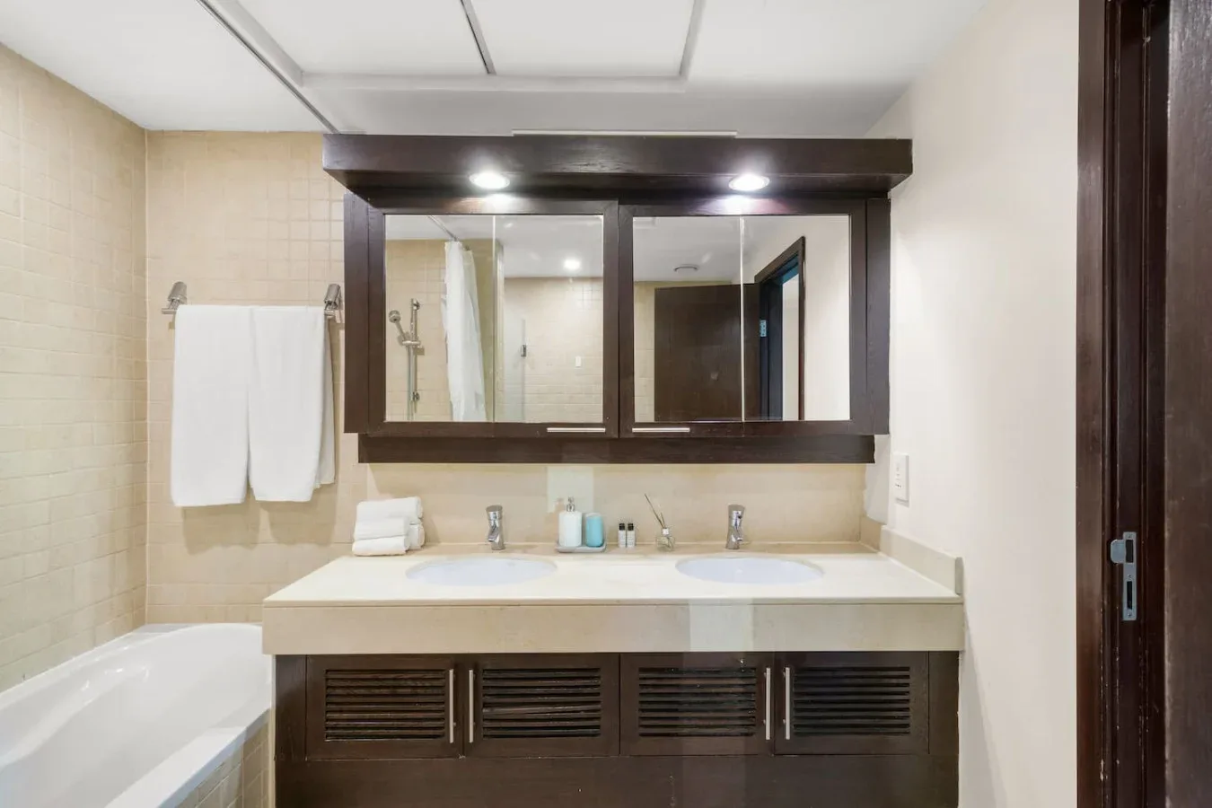 A bathroom vanity with a wide mirror and a bathtub along the side.