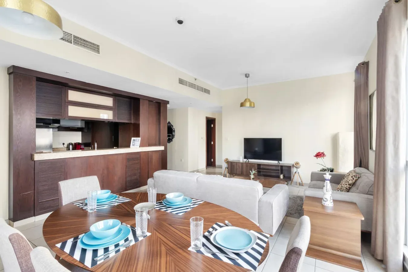 A bright living and dining area with a television and a set dining table.