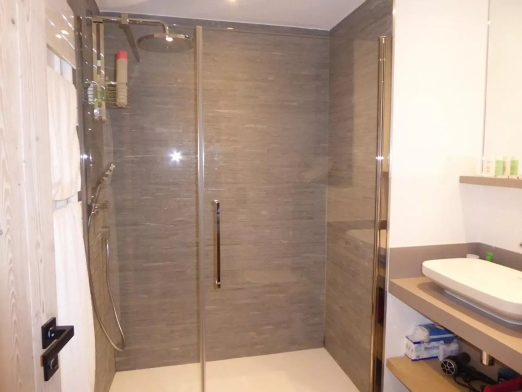 Un baño con ducha de vidrio y lavabo con mueble.