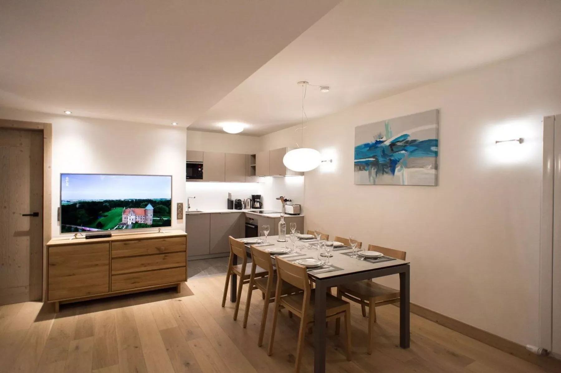 Dining area with a set table beside a compact kitchen and television.