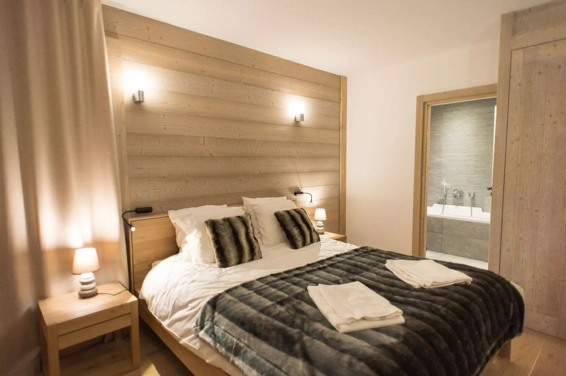 Un dormitorio con cama, mesillas y un baño contiguo.