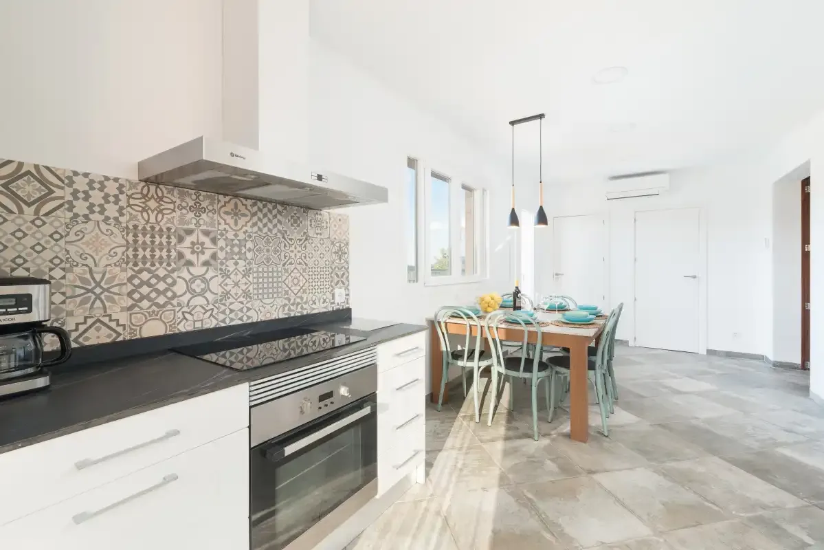 Una cocina luminosa y zona de comedor con una mesa larga junto a los mostradores.