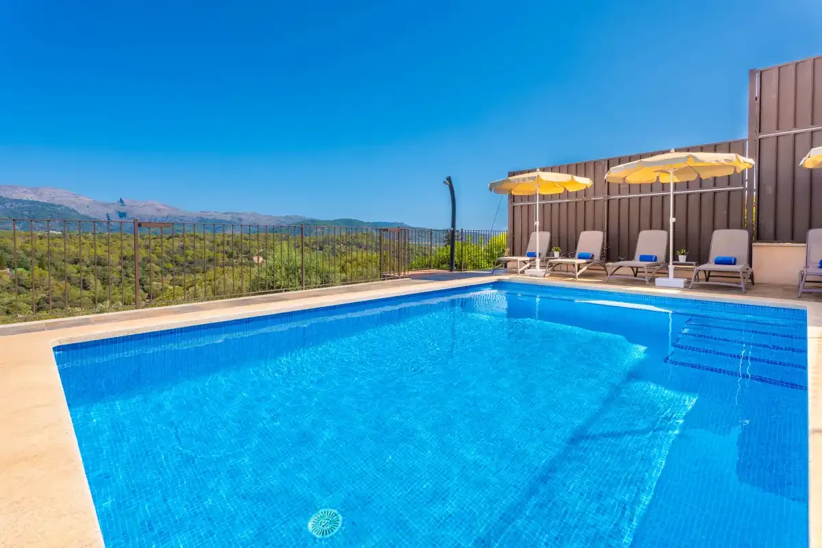 Una piscina al aire libre con tumbonas y sombrillas amarillas junto a ella.