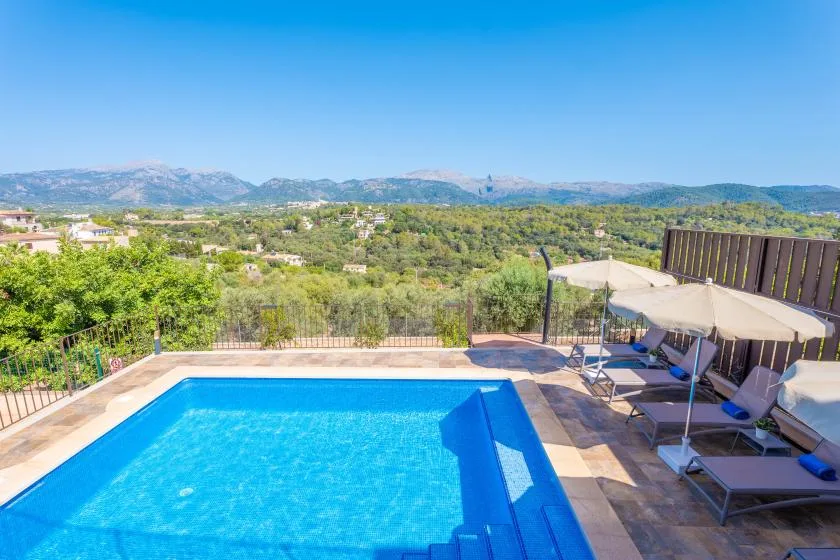 Una piscina al aire libre ofrece vistas de colinas verdes y montañas lejanas.