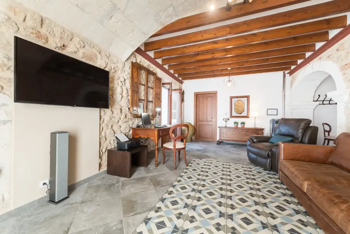 Una sala de estar con asientos de cuero, un televisor y vigas de madera vistas.
