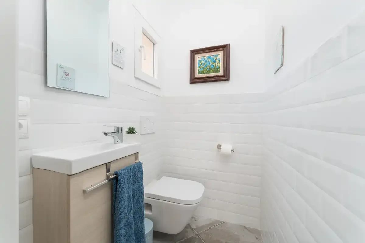 Un baño luminoso con lavabo, inodoro y una obra enmarcada.