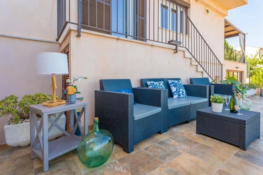 Una zona de estar al aire libre con muebles de mimbre oscuro junto a una escalera exterior.