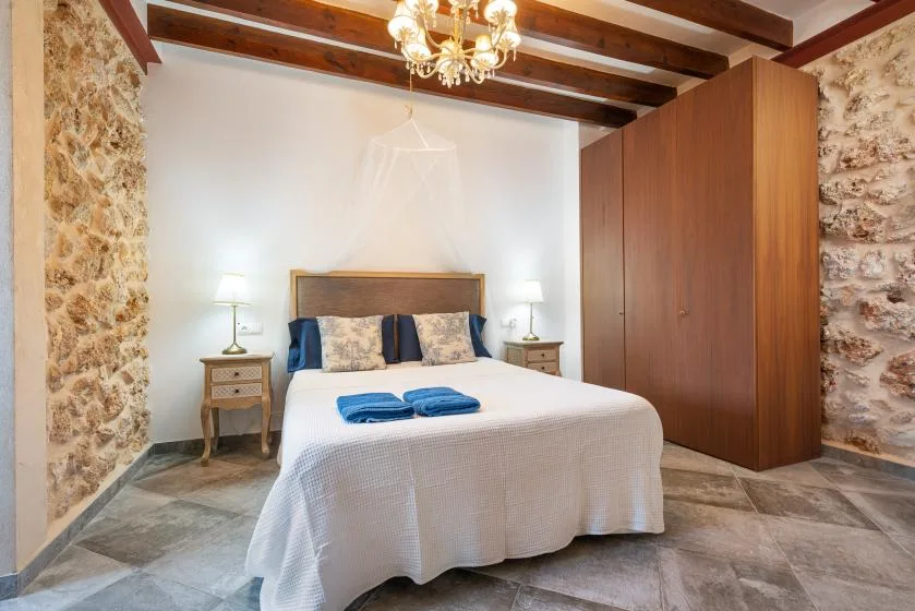 Un dormitorio con una cama, mesitas de noche y un armario de madera.