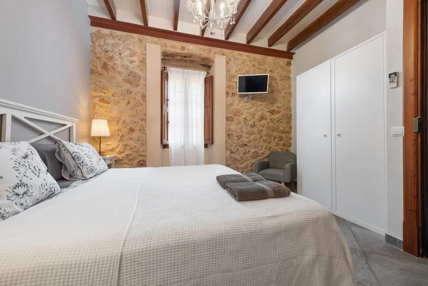 Un dormitorio con una cama grande, paredes de piedra y vigas expuestas en el techo.