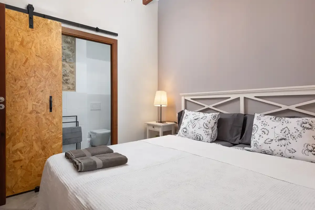 Un dormitorio con una cama grande y una puerta corredera al baño.
