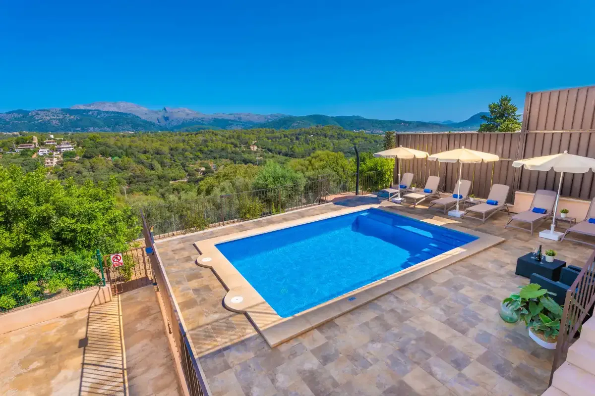 Una piscina al aire libre y un patio dan a un paisaje verde.