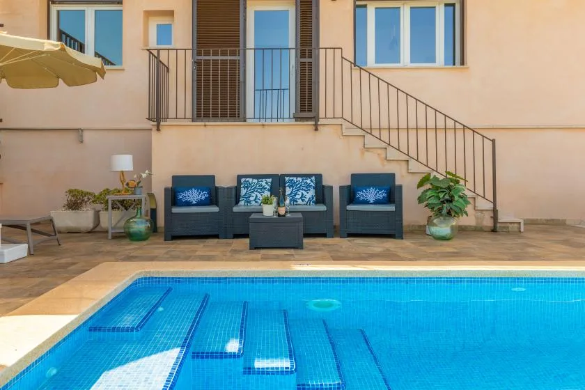 Una piscina ocupa el primer plano, con asientos de patio junto al edificio.