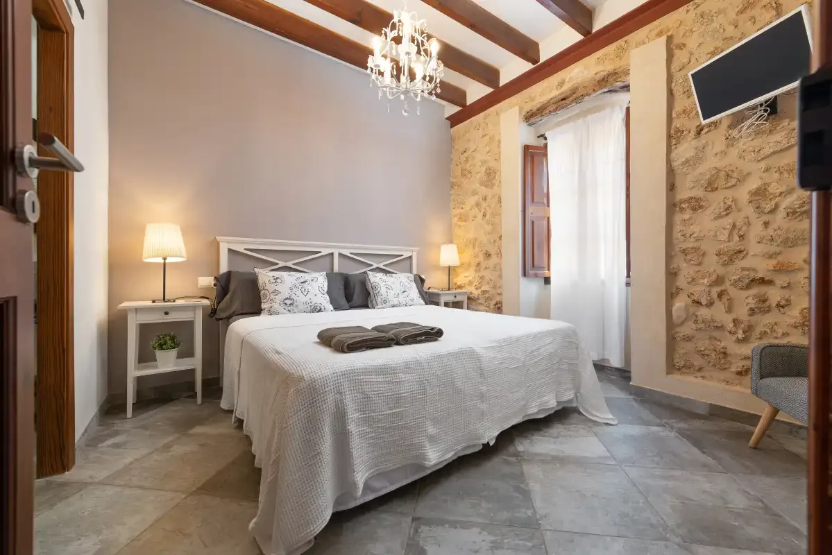 Un dormitorio con una cama, mesitas de noche y vigas de techo expuestas.