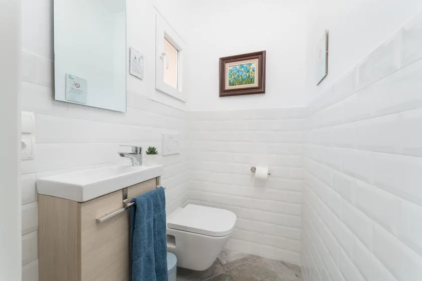 Un baño luminoso con lavabo, inodoro y una obra enmarcada.