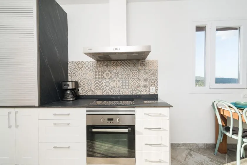 Una cocina luminosa con horno empotrado, salpicadero estampado y ventana.