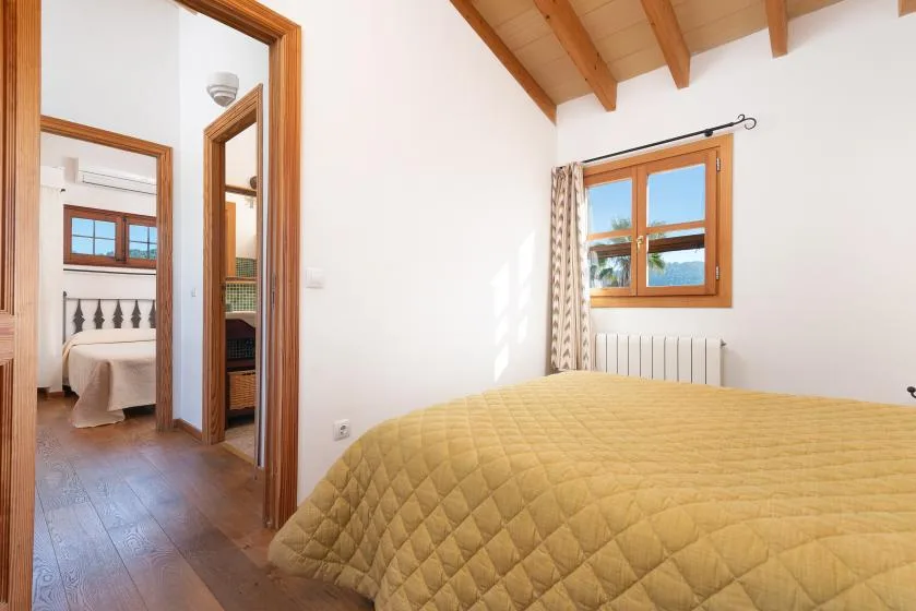 A bedroom with a quilt-covered bed beneath a sloped wooden ceiling.